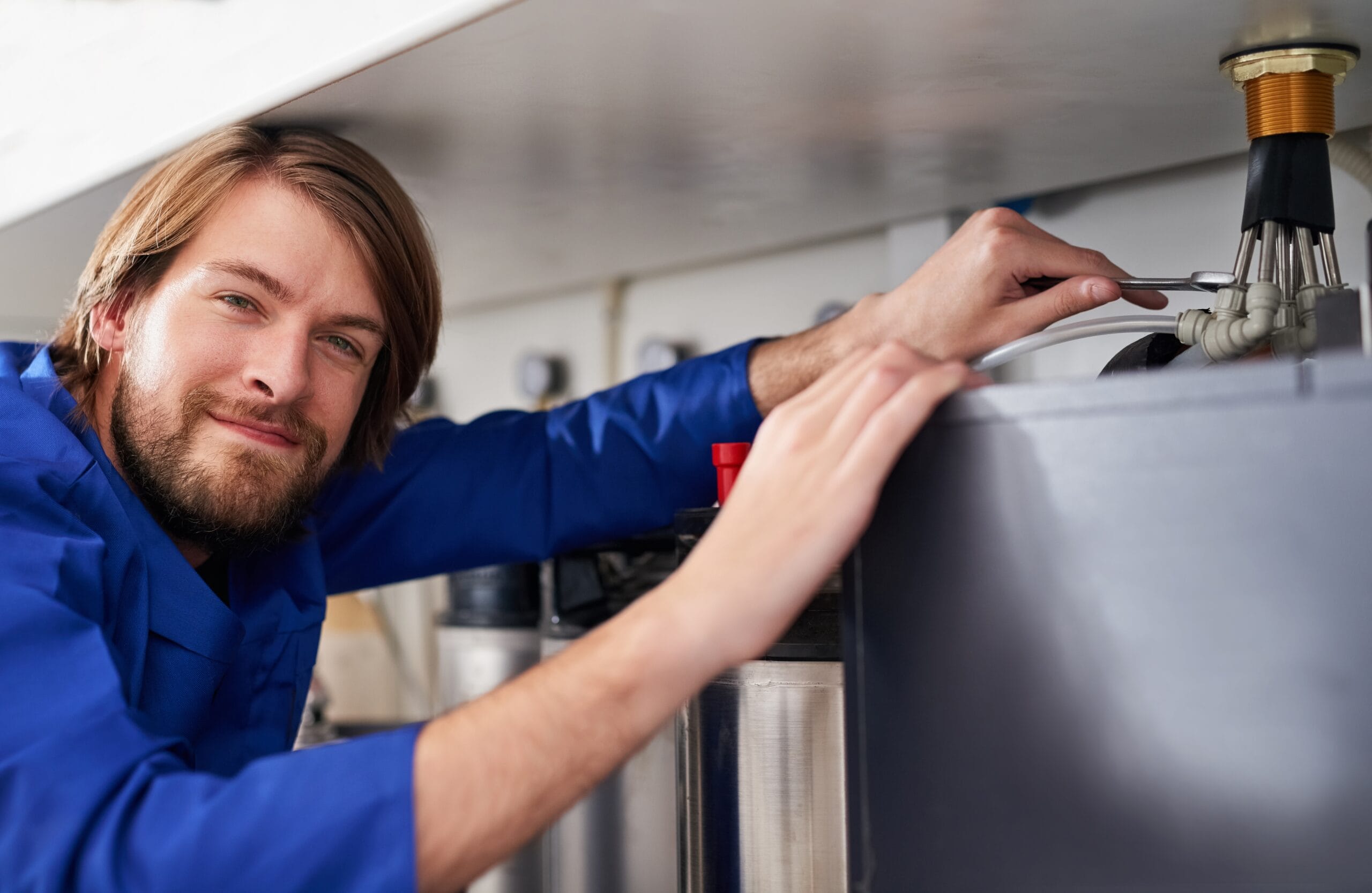 Technician servicing a residential water heater tank in Claremont
